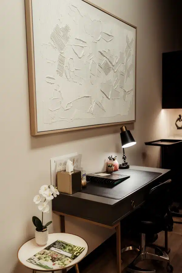 IPL Photofacial in Waunakee, WI 4 Consultation desk at Loure Aesthetics with a dark leather top, lit desk lamp, succulent and orchid